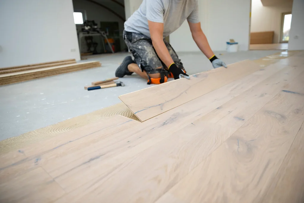 Contractor installing hardwood flooring on adhesive